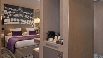 A hotel room with a bed, a coffee maker, and a small table with cups and a vase of flowers.