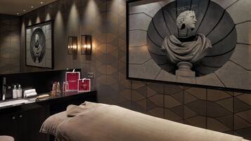 Relax in a serene spa room with a circular artwork, sleek reception desk, and neatly arranged toiletries.