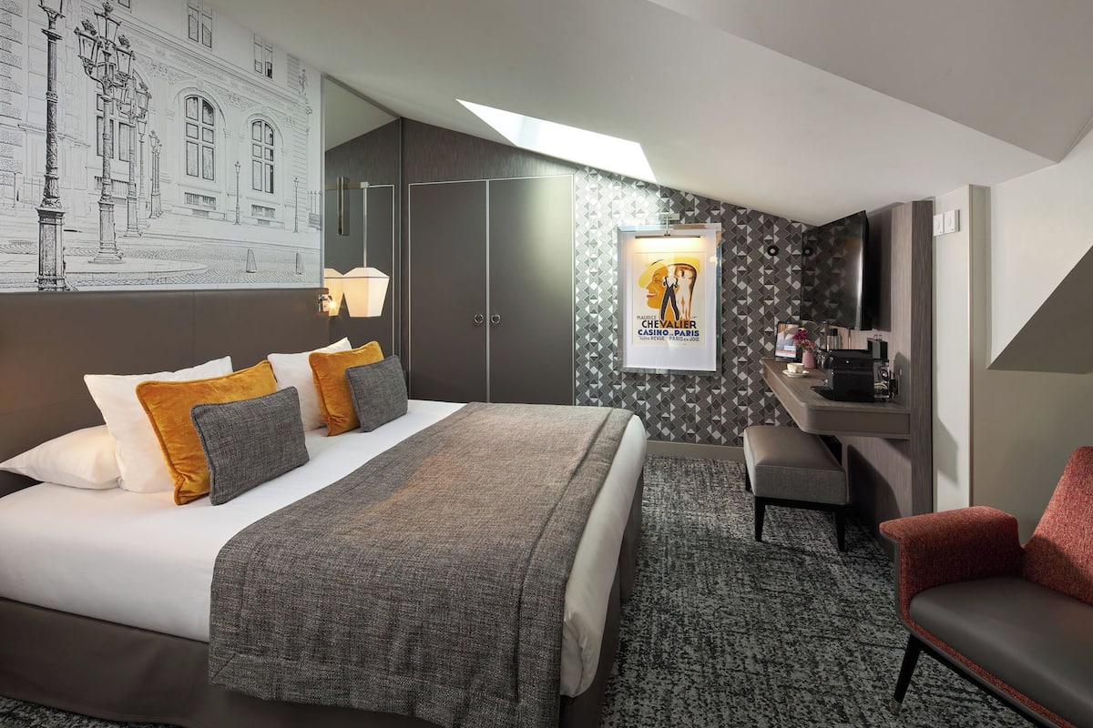 A modern hotel room with a large bed, a desk, and a seating area.