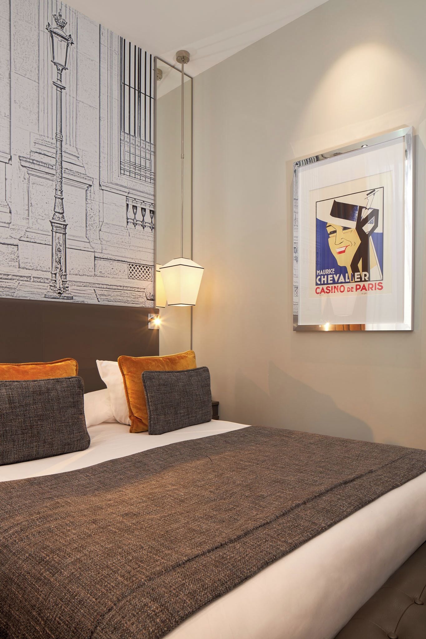 A hotel room with a bed, a lamp, a framed poster, and a wall with a drawing.