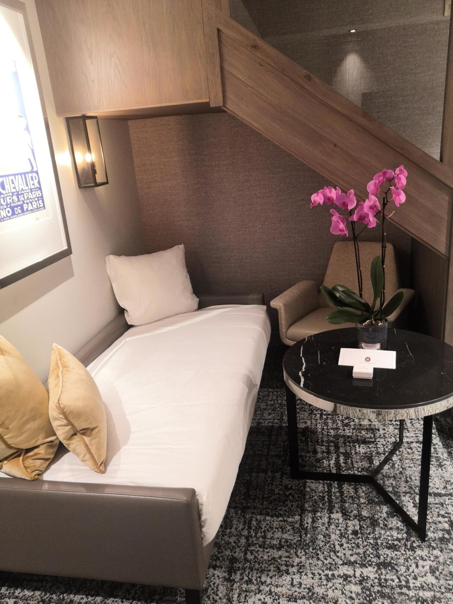 A hotel room with a bed, a sofa, a small table, and a potted plant.