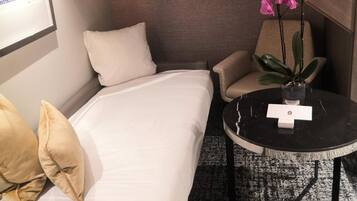 A hotel room with a bed, a sofa, a small table, and a potted plant.