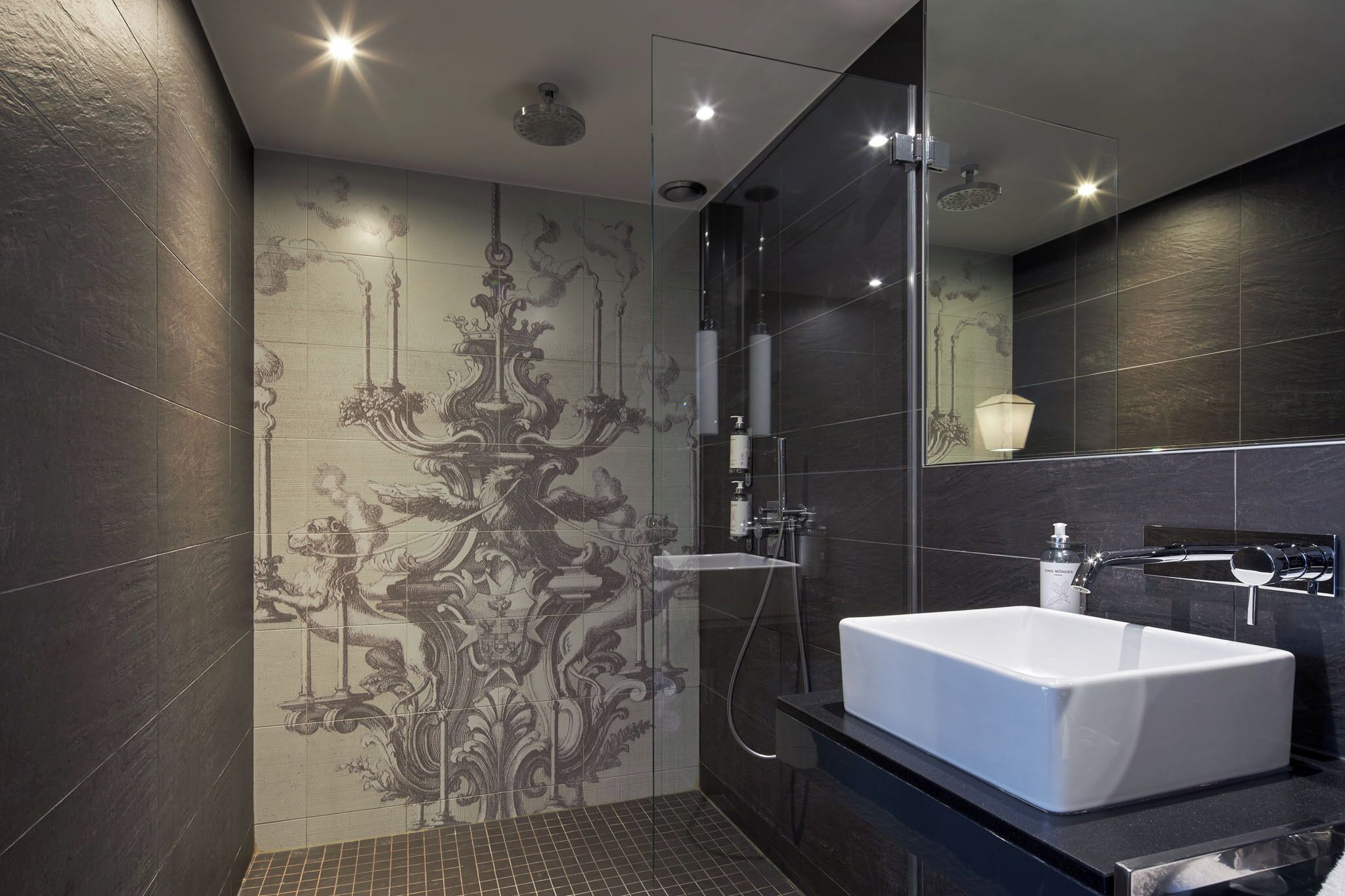 Un baño moderno con una bañera blanca grande, una ducha con cerramiento de vidrio y azulejos decorativos en la pared.