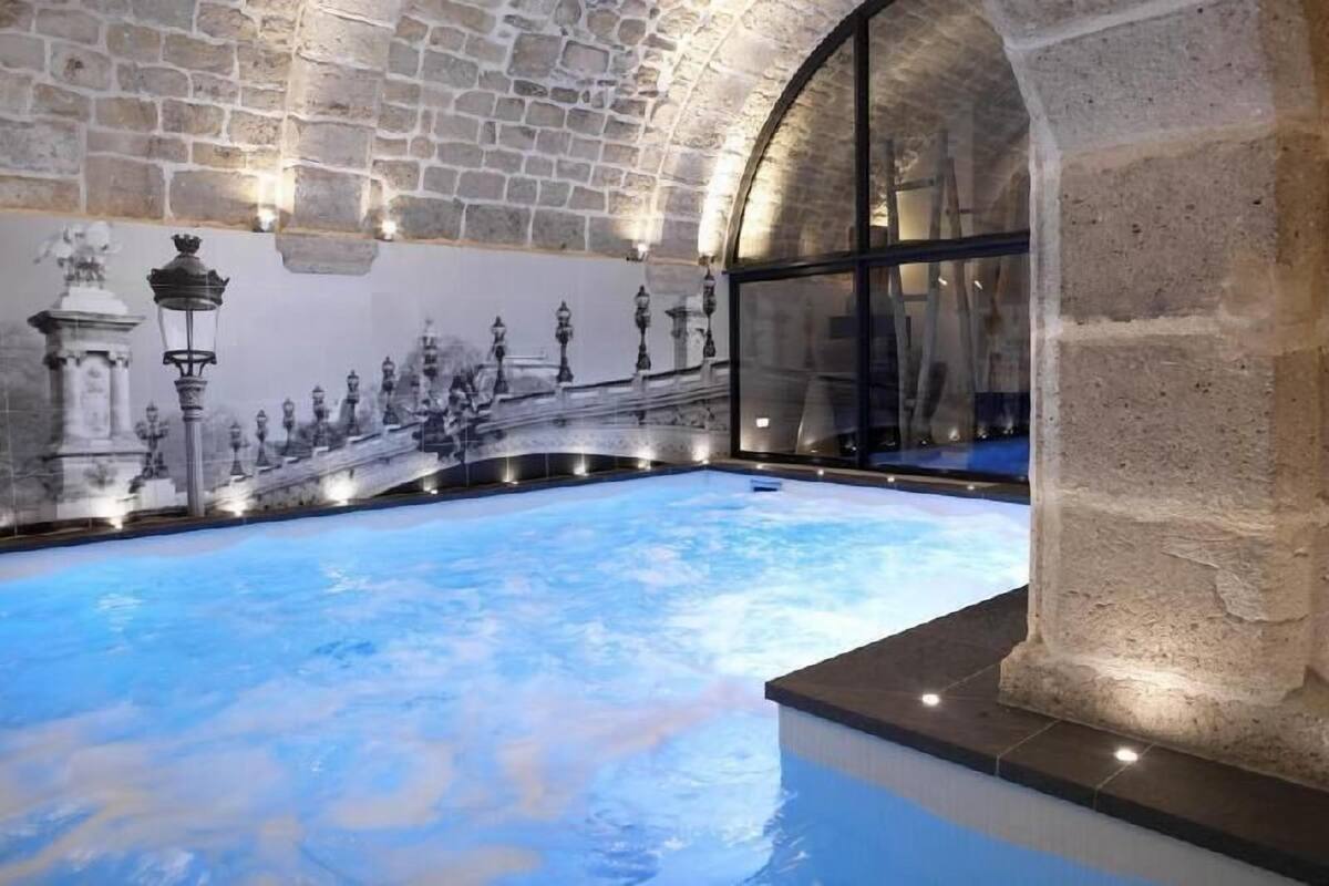 An indoor swimming pool with stone walls and a mural.
