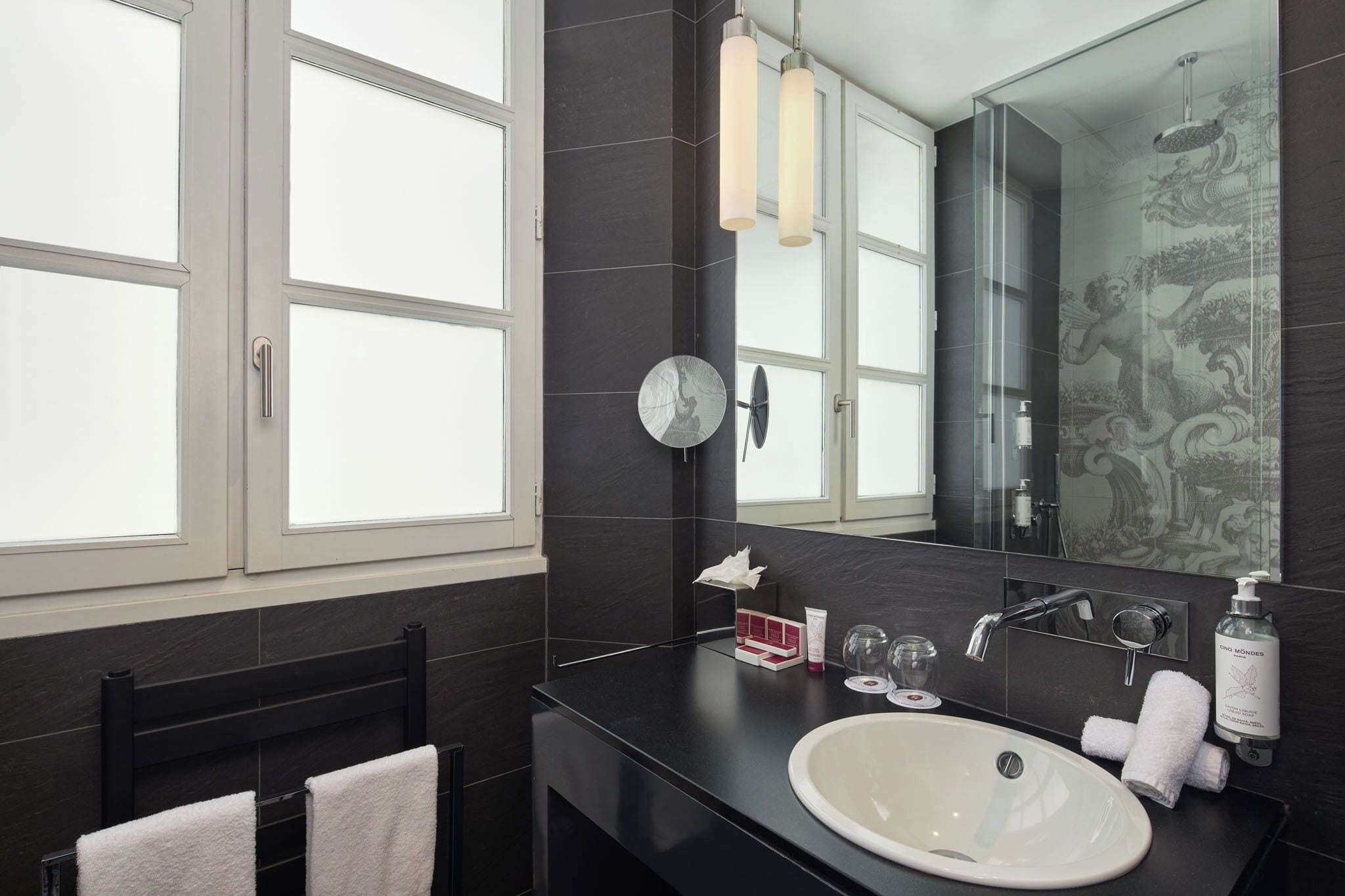Un baño moderno con un espejo grande, un lavabo blanco y una ducha con mampara de vidrio.
