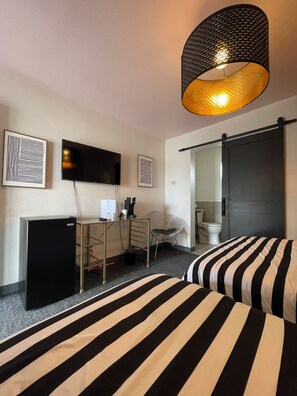A hotel room with a bed, a desk, a television, and a sliding door. - Rainbow Motel (Greeley)
