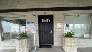 A building entrance with a black door labeled "hello," a "notice" sign, and a "no cash is kept on premises" sign.