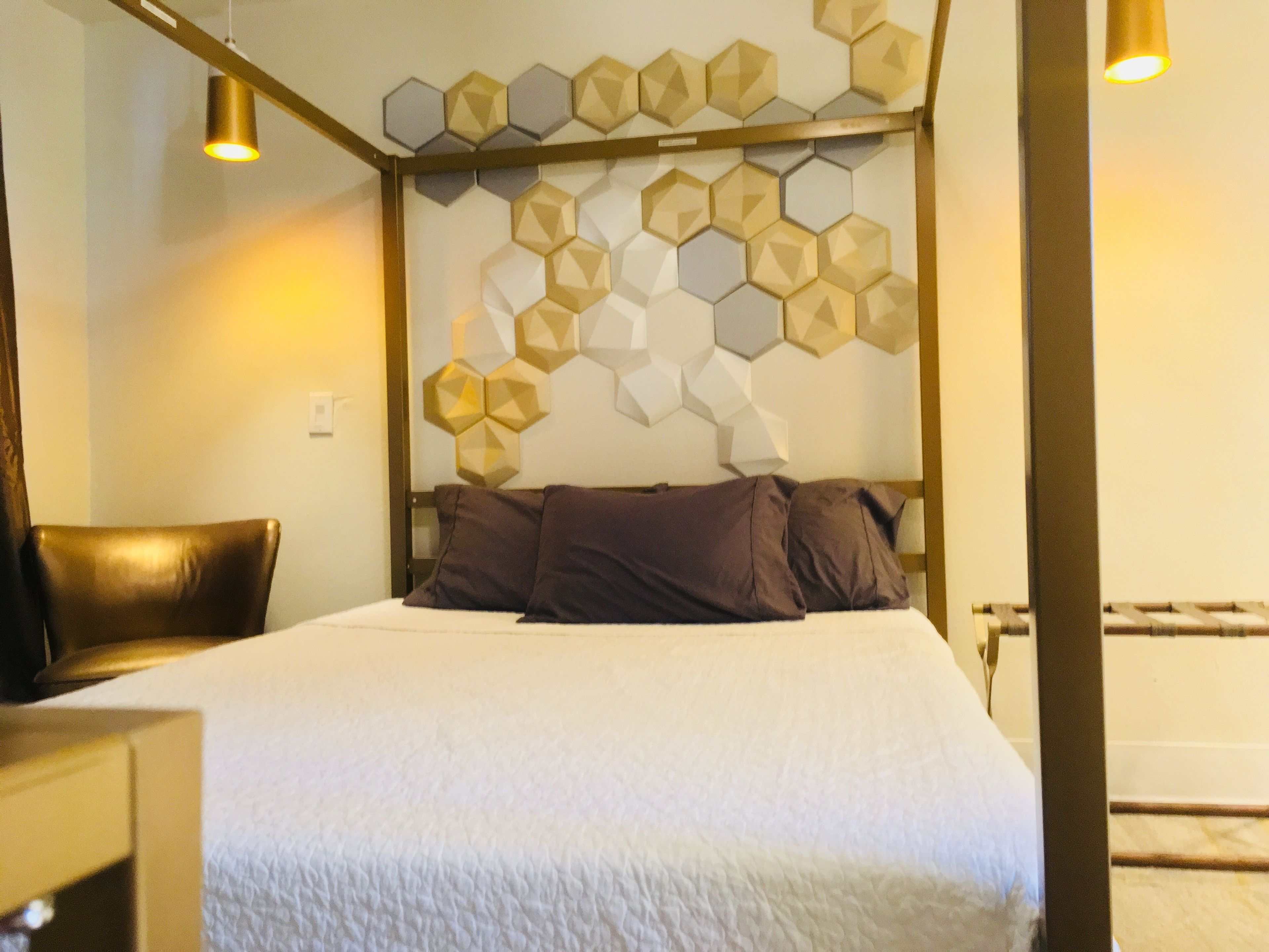 Cama bem arrumada com um design geométrico na parede acima.