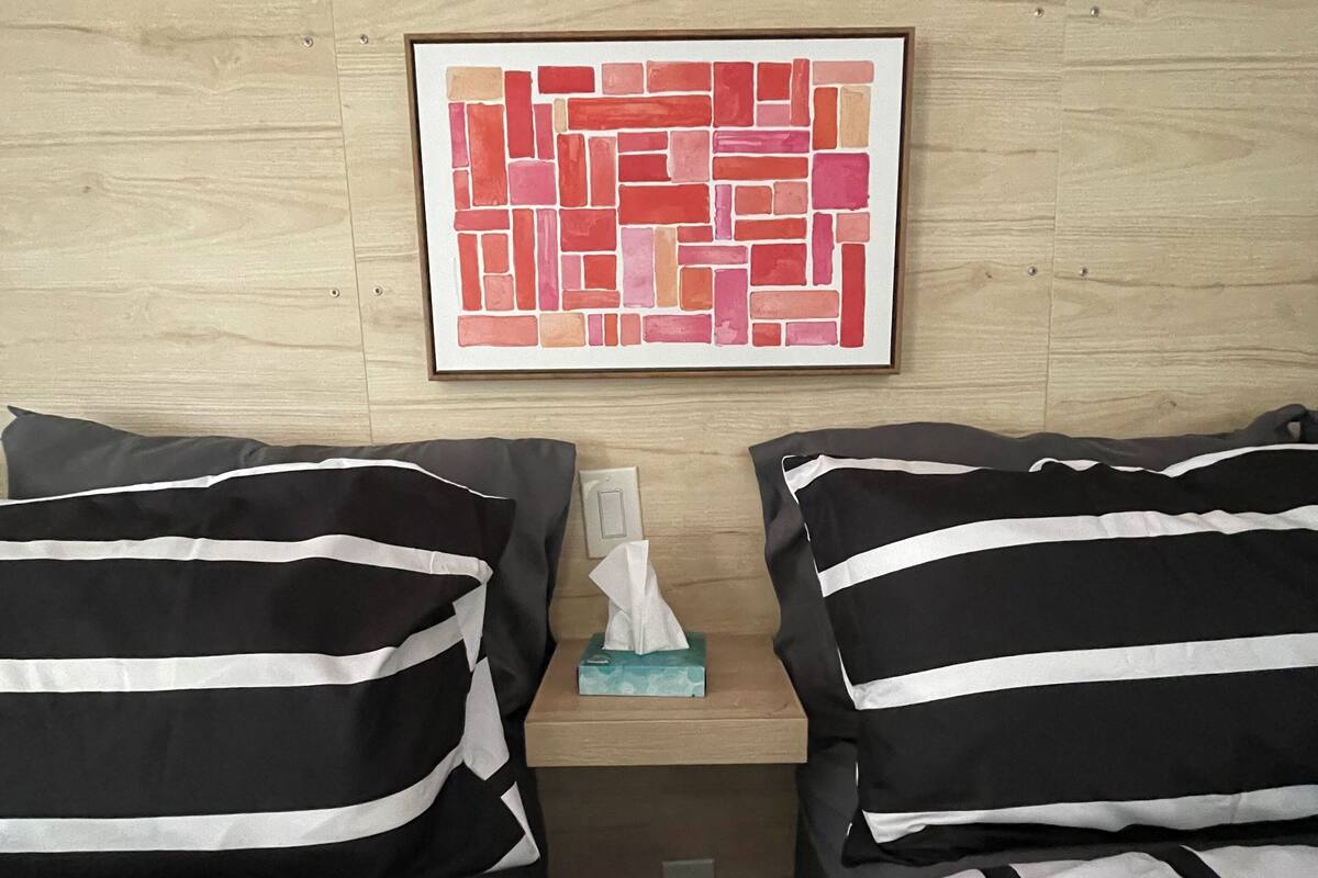 A hotel room with two beds, a framed artwork on the wall, and a tissue box on the nightstand.