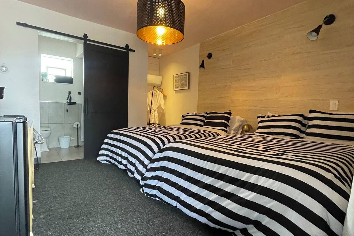 A hotel room with a bed, a desk, and a bathroom visible through an open door.