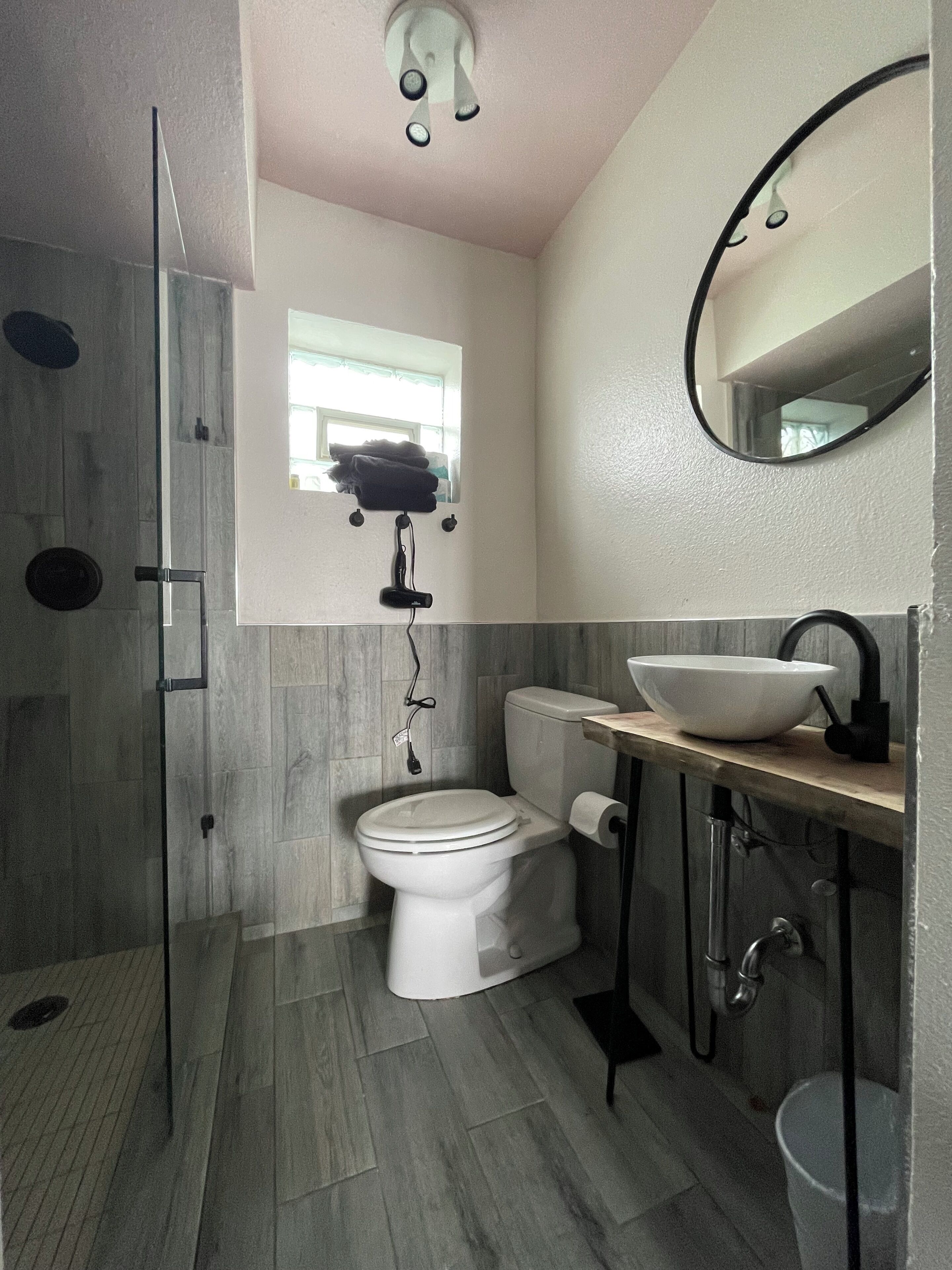 A modern bathroom with a glass shower enclosure, a toilet, a sink with a basin, and a mirror.
