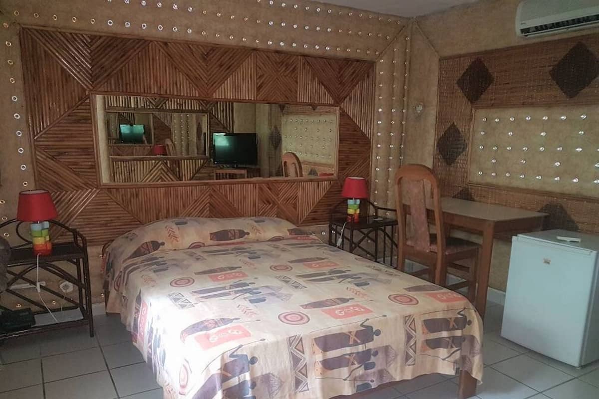 Un dormitorio con una cama, un escritorio, una silla, un televisor y un refrigerador pequeño.