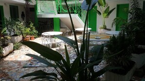 Un patio con suelo de baldosas, barandillas verdes y macetas con plantas.