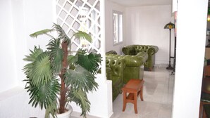 Una sala de estar con un sofá de cuero verde, una mesa de centro de madera y una planta en maceta.