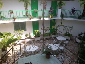 A multi-level outdoor patio with tiled flooring, metal railings, and potted plants. - Le Patio (Libreville)