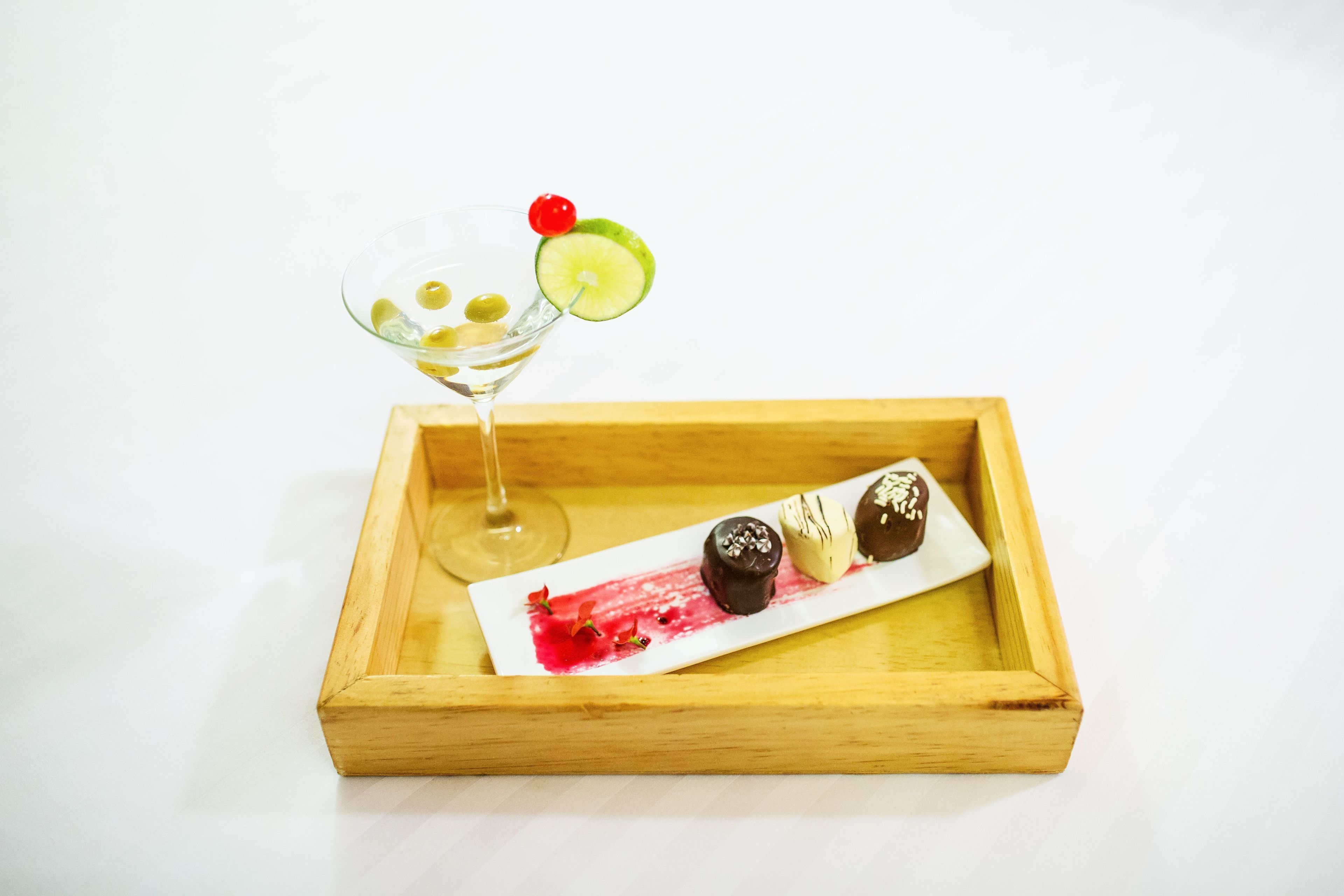 Un plateau en bois avec un verre à martini et une assiette de desserts.