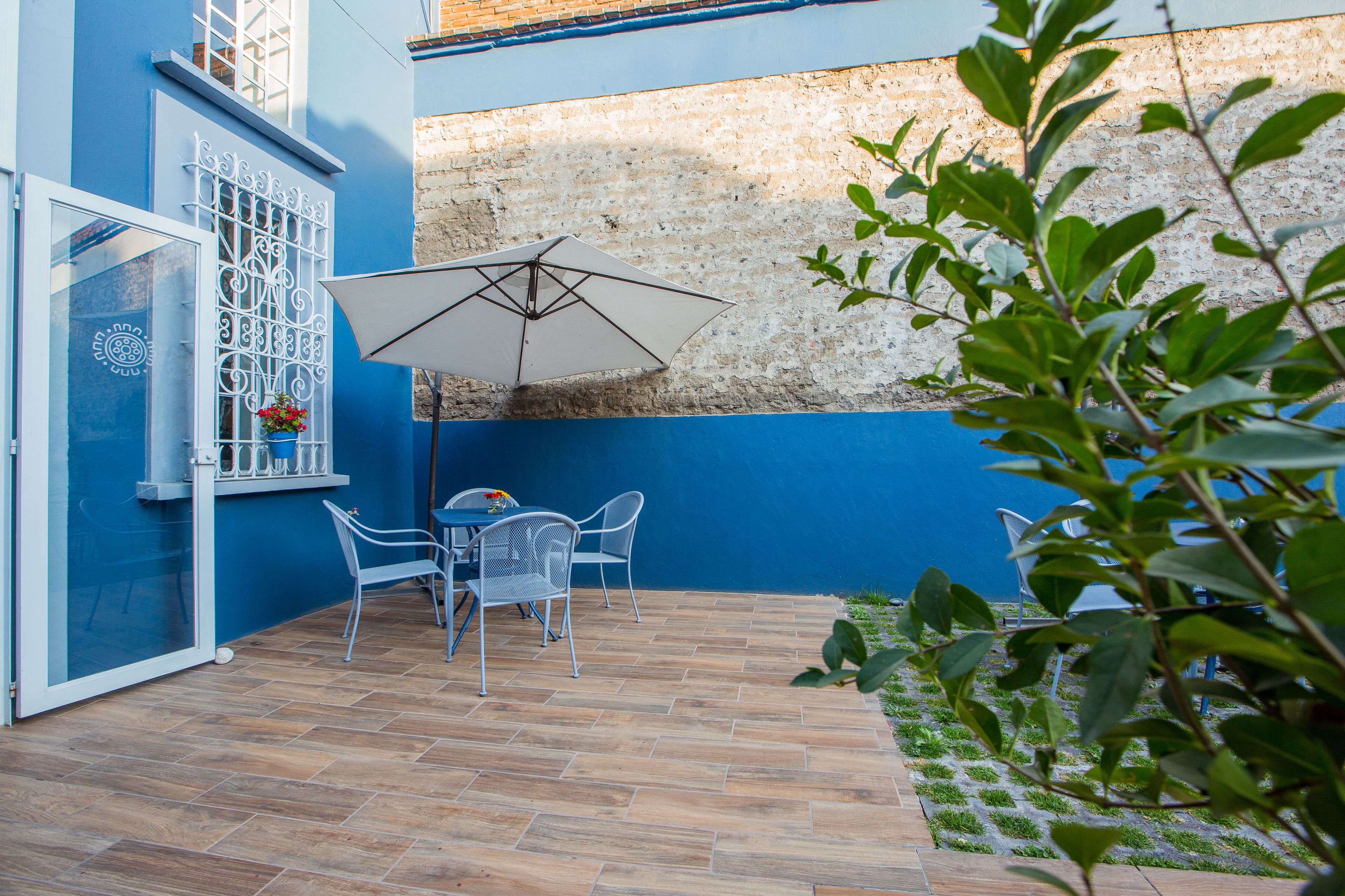 A patio with a table and chairs, a white umbrella, and a window with decorative metal bars.