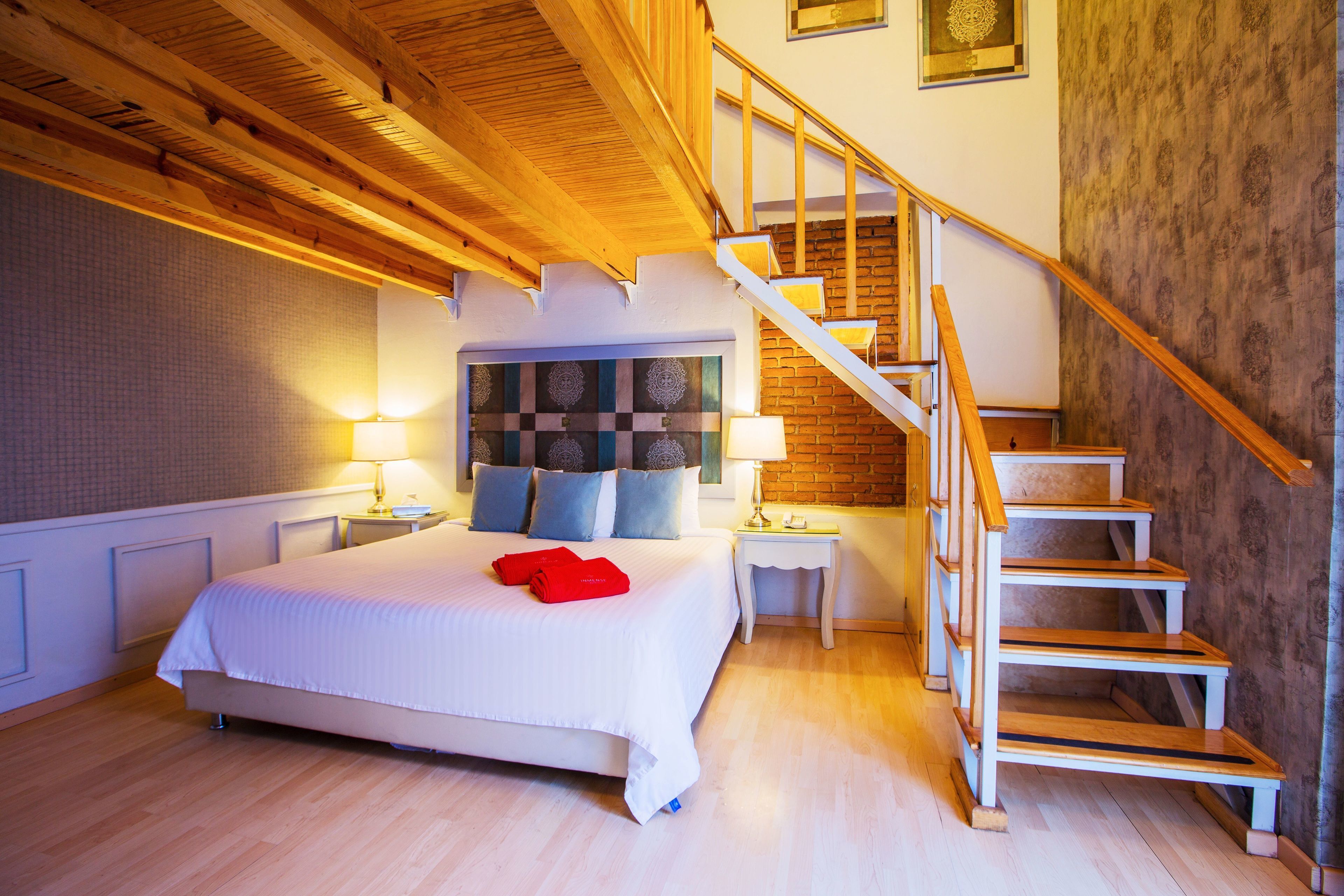 Un dormitorio con una cama grande, una escalera de madera y un cabecero con diseño estampado.