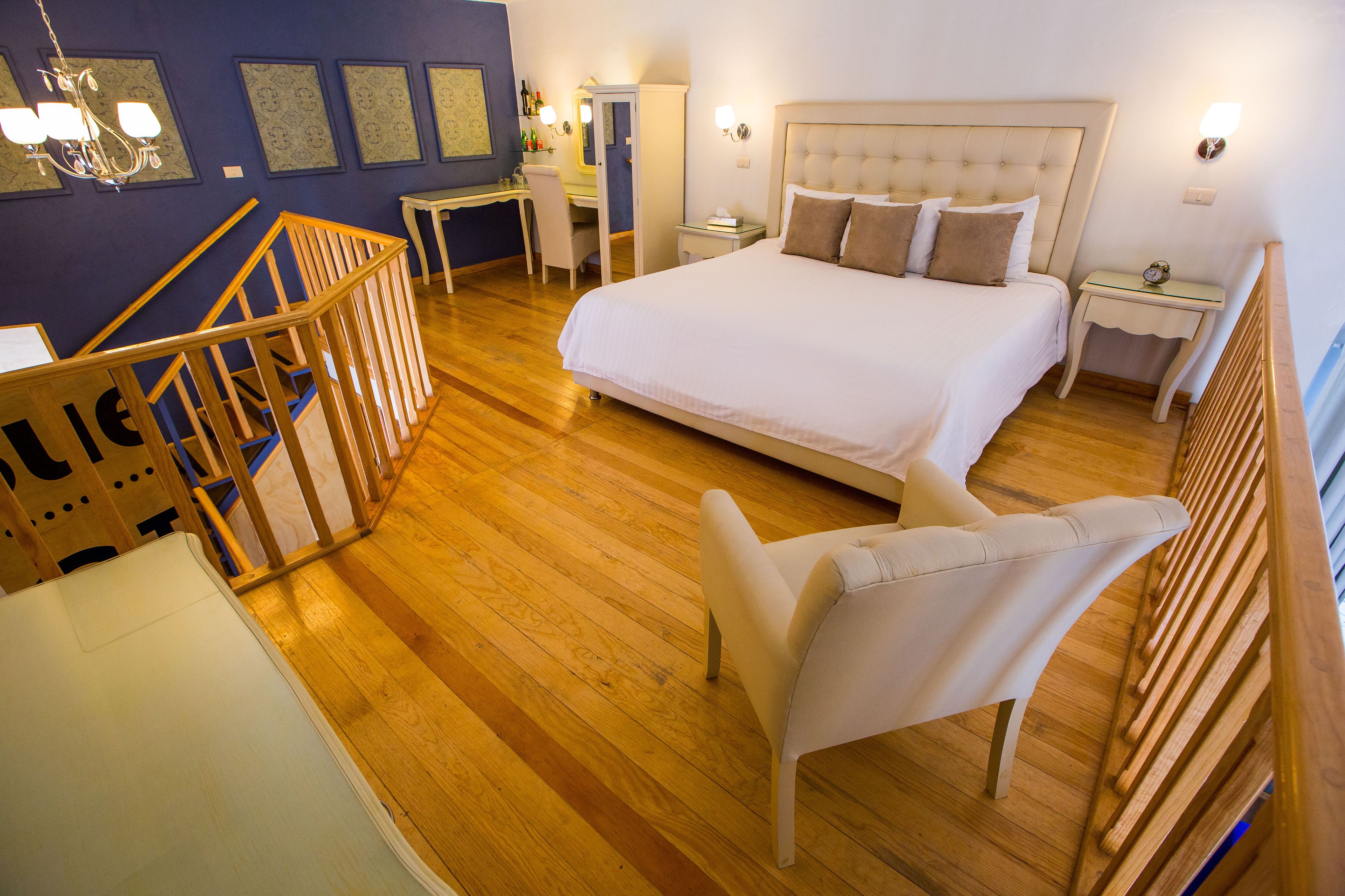 A hotel room with a large bed, a desk, a chair, and a small table.