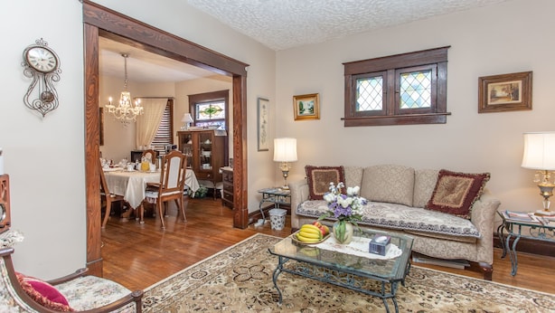 A living room with a sofa, coffee table, and a dining area with a table and chairs. - Ambiance by the Falls B&B (Niagara Falls)