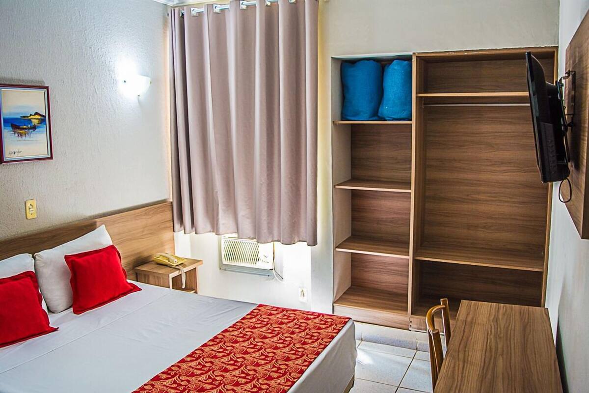 Habitació d'hotel amb llit, escriptori, cadira, armari i televisió.