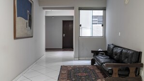 A living room with a black leather sofa, a patterned rug, and a painting on the wall. - Carlton Express - Antigo Plaza Hotel (São José dos Campos)