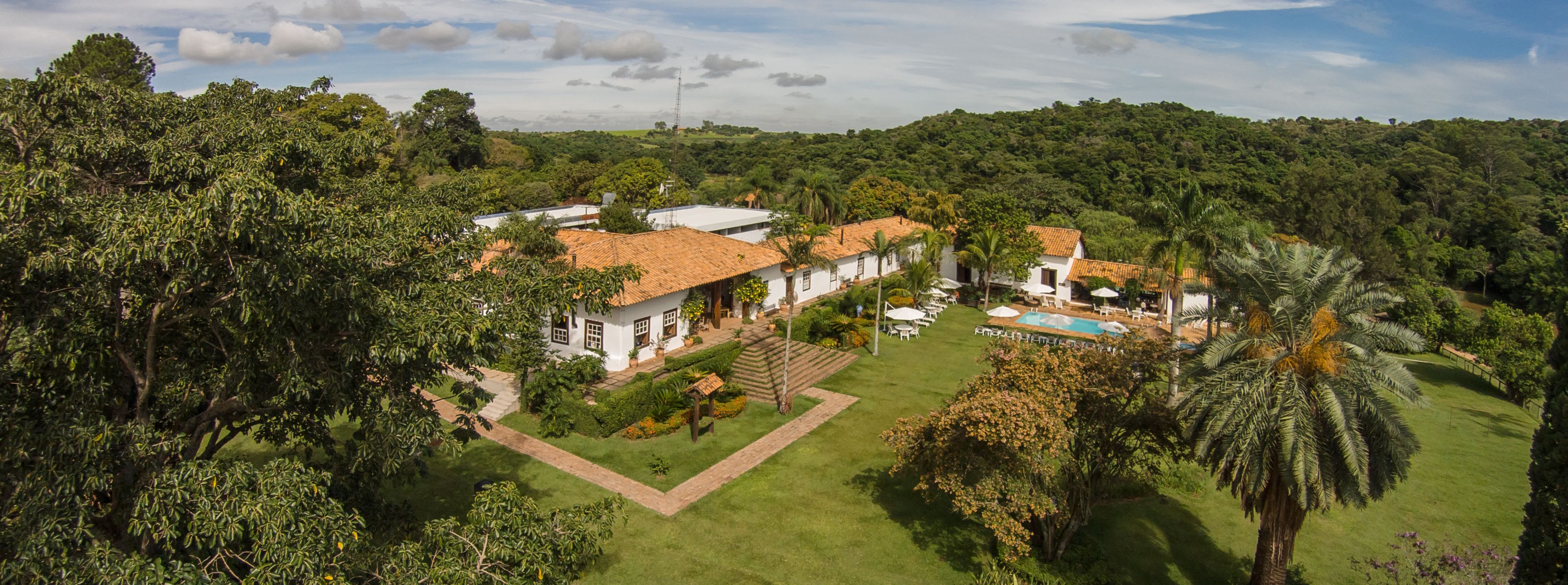 Uma grande propriedade com várias construções, piscina e vegetação exuberante.