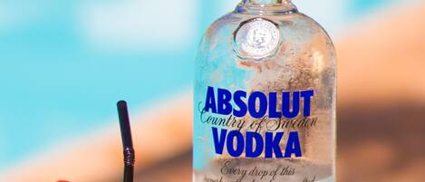 Une bouteille de vodka Absolut et un verre contenant une tranche de pomme et une paille.