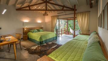 Quarto com escrivaninha de madeira, duas camas, um tapete grande e vista para o exterior.