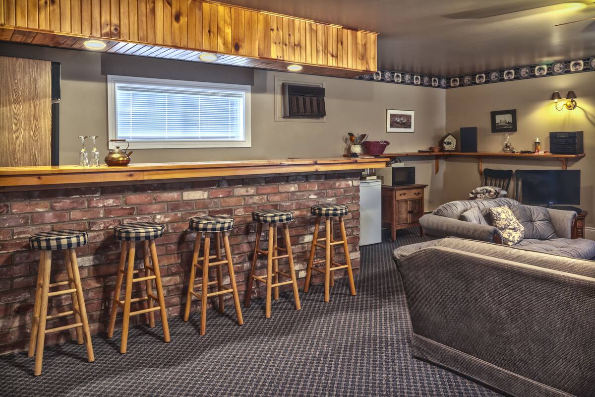 A bar area with wooden stools, a brick wall, and a seating area with a sofa and chairs.