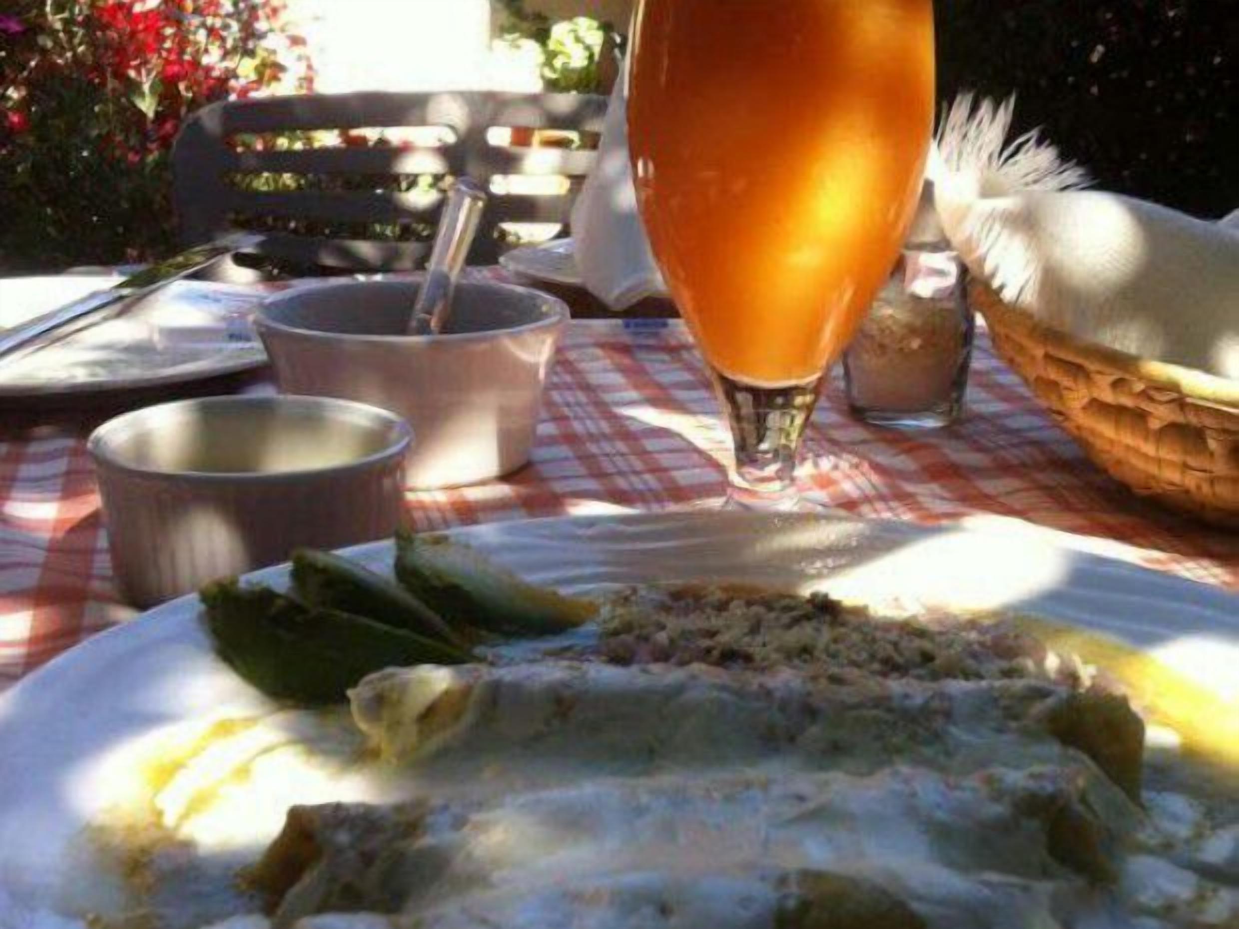 Un tavolo con una tovaglia a quadri, un bicchiere di bevanda arancione e un piatto con avanzi di cibo.