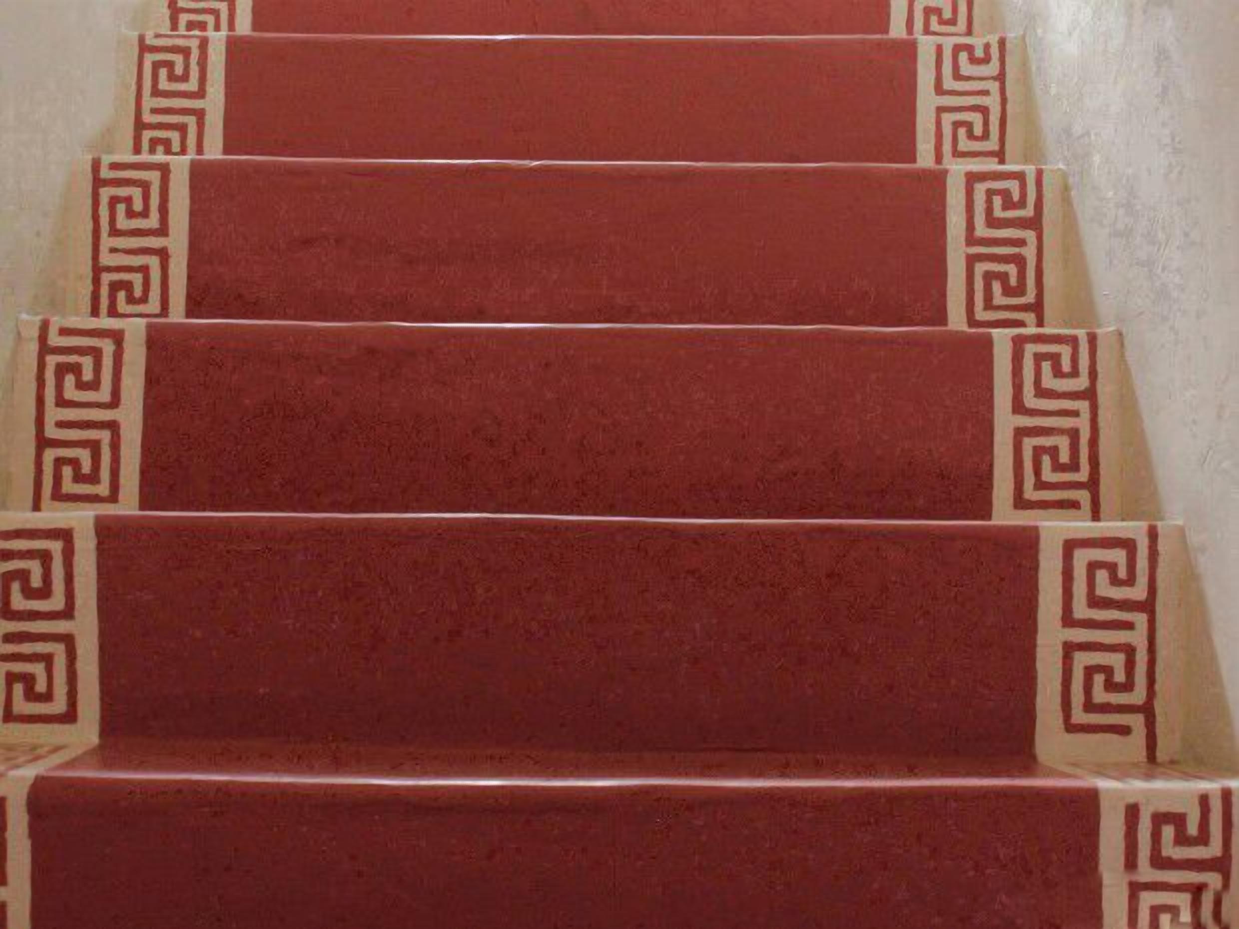 A set of red carpeted stairs with a decorative border.