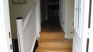 A wooden staircase with white railings leading to a dark interior. - Sea Whale Cottages (Middletown)
