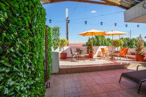 A terrace with a tiled floor, outdoor seating, potted plants, and string lights. - Hotel Nacional (Oaxaca)