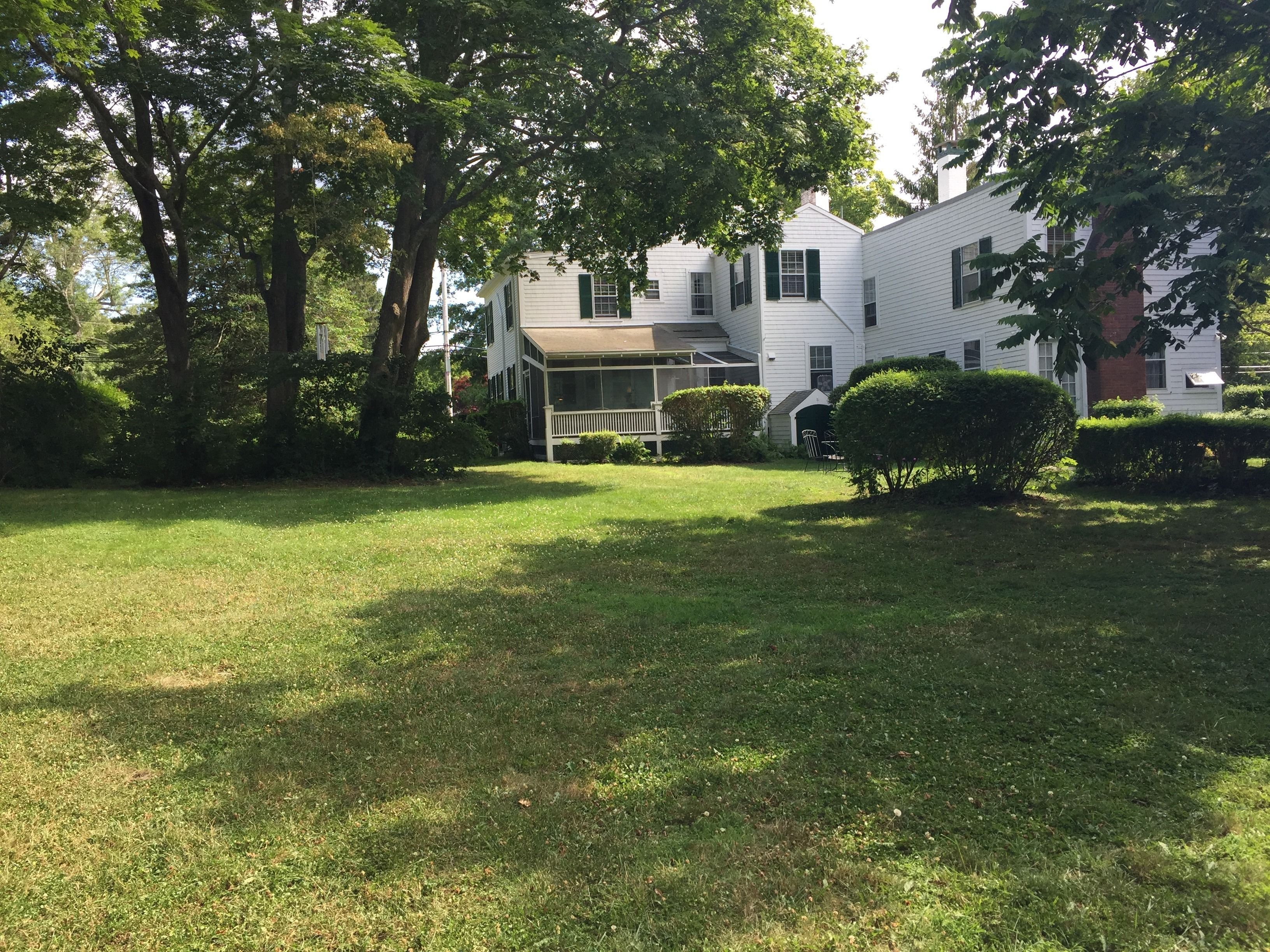 A white two-story house with a covered porch and a well-maintained lawn.