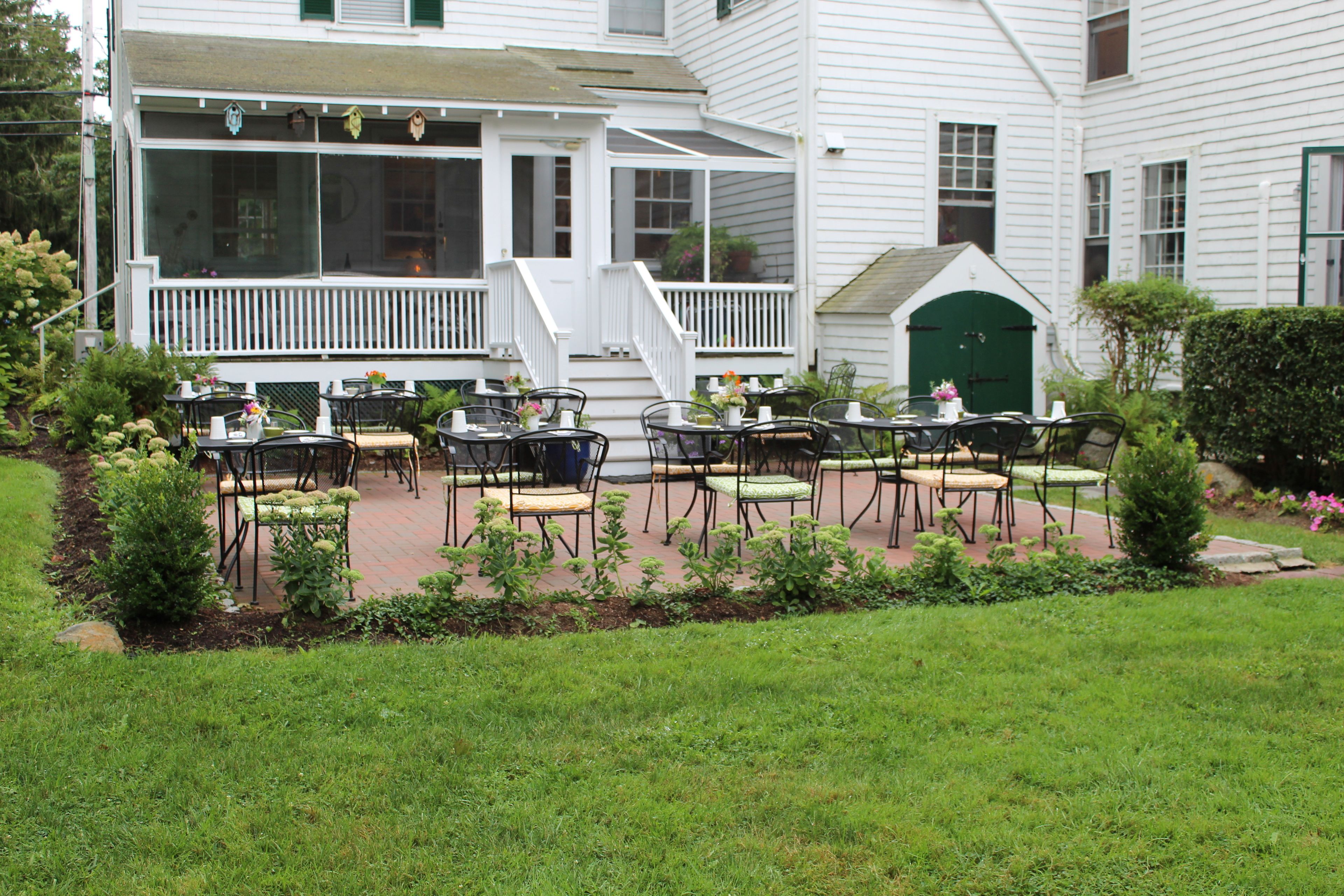 A white building with a covered patio area featuring outdoor seating with tables and chairs.