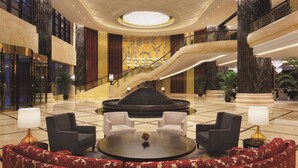 A grand lobby with a central staircase, seating area, and a chandelier. - Wyndham Urumqi North (Miquan)