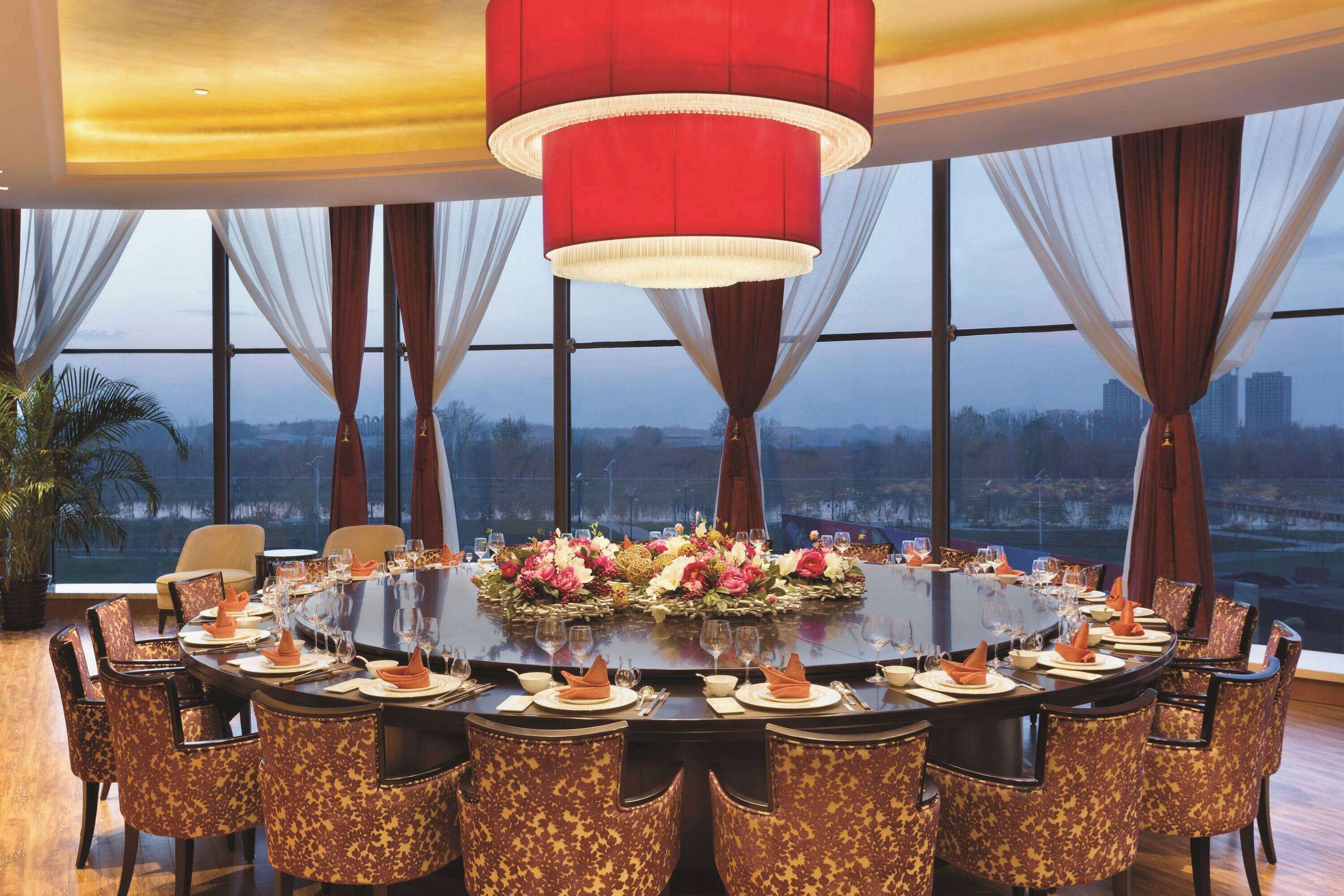 A conference room with a round table, chairs, and a city view.