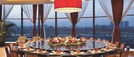 A conference room with a round table, chairs, and a city view.