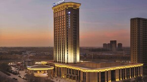 A high-rise hotel with a prominent sign, multiple floors, and a well-lit exterior. - Wyndham Urumqi North (Miquan)