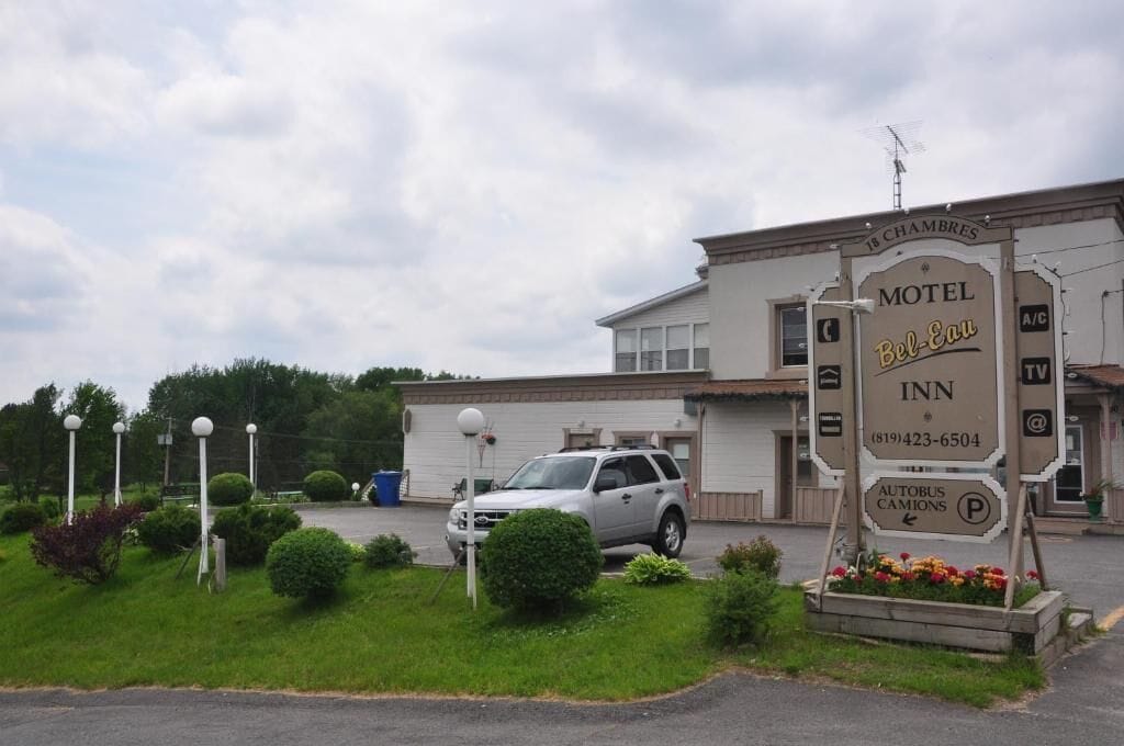 A motel named Bel-Eau Inn with a sign indicating 18 chambers, a TV, and an autobus camions service.