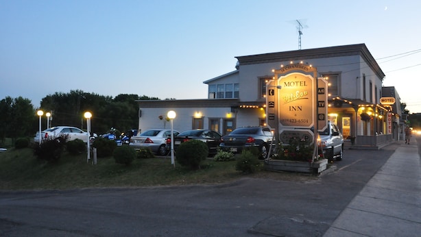 A motel with a signboard, parked cars, and a well-lit entrance.