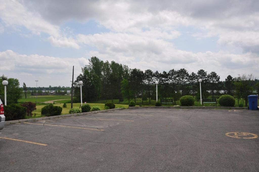 Un parcheggio con cielo sereno, alberi e un campo da golf in lontananza.