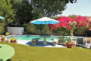 Relax by the pool surrounded by lush greenery and a neatly trimmed lawn.