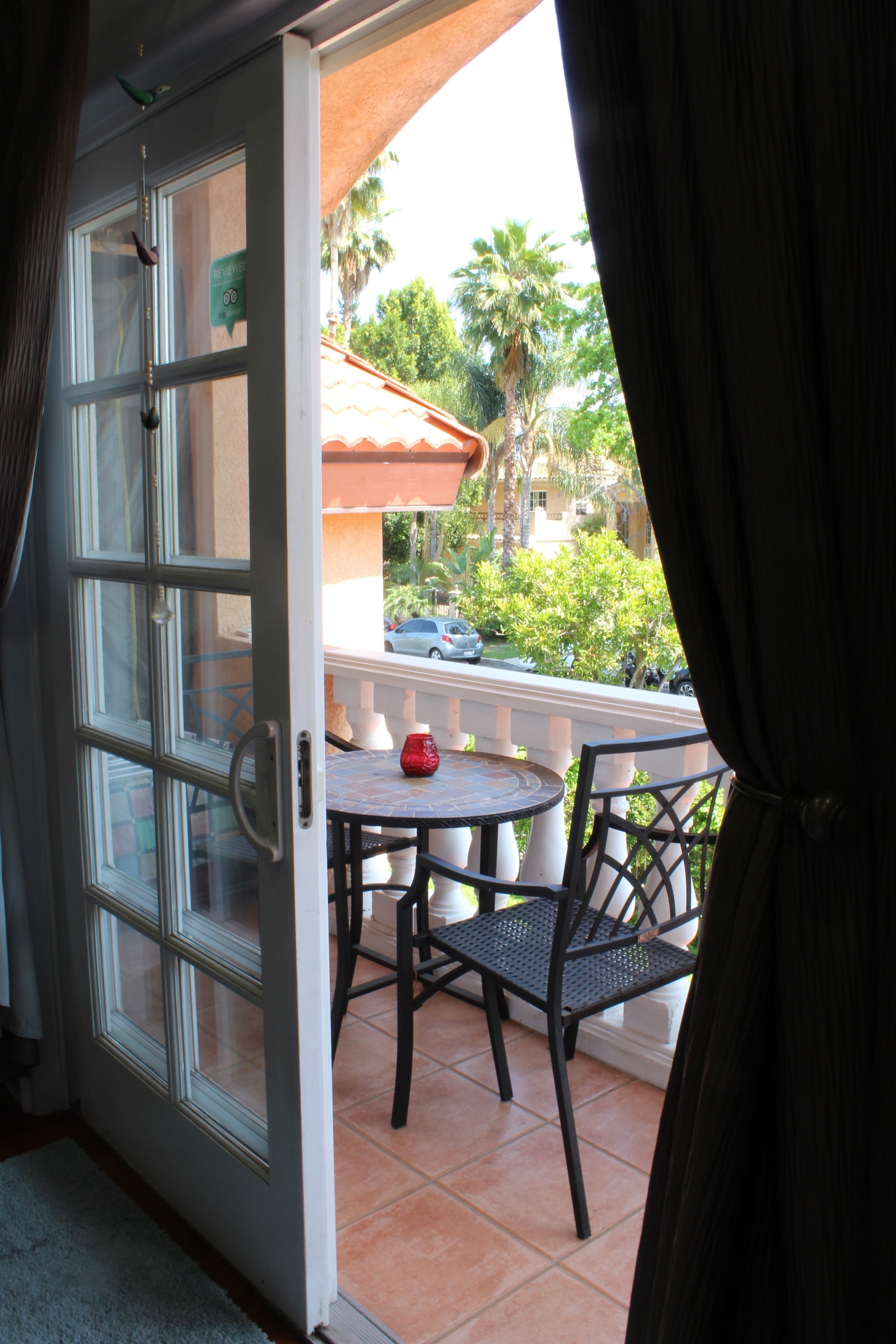 A room with a sliding glass door leading to an outdoor balcony with a tiled floor and a small round table with chairs.