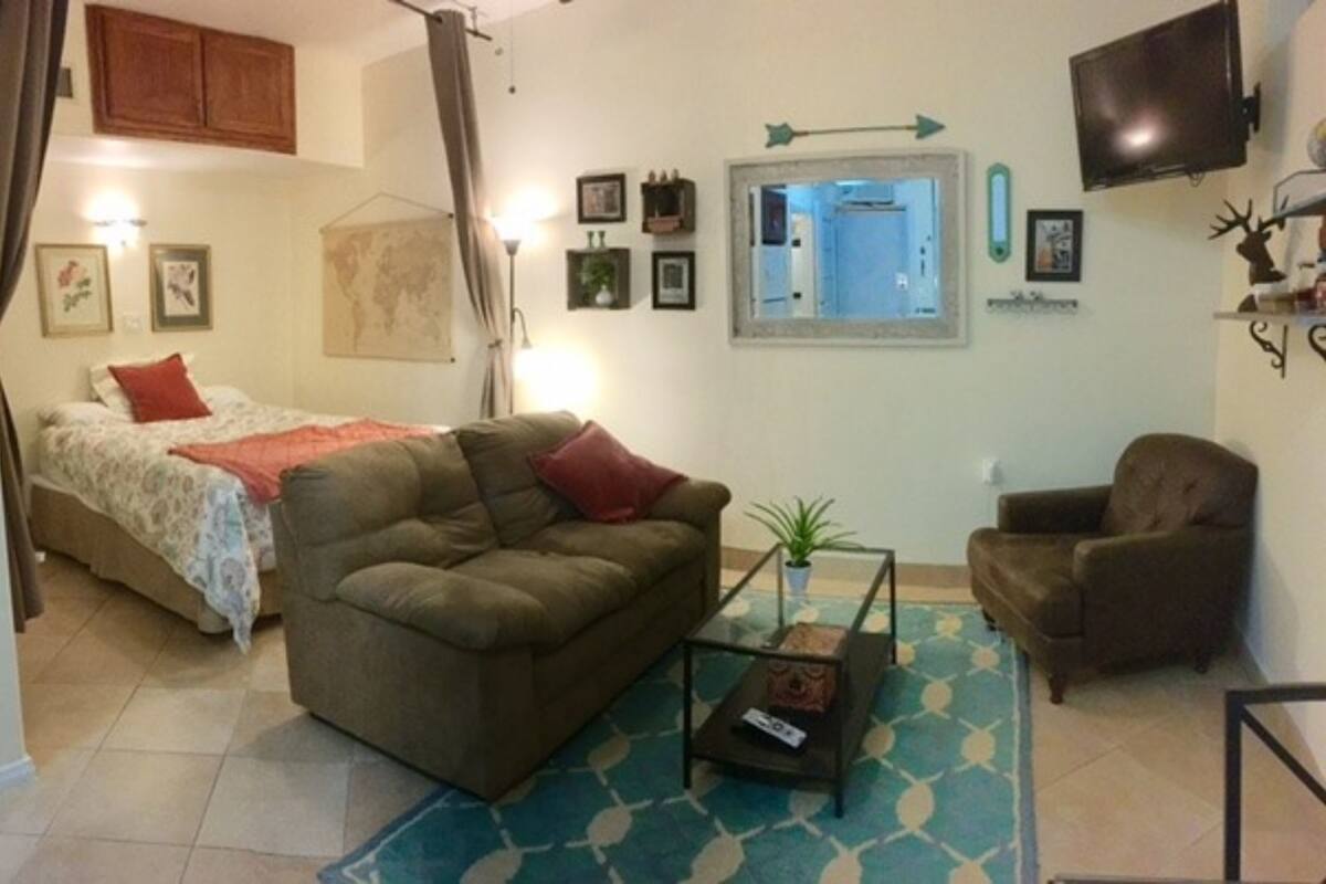 A cozy living room with a bed, a sofa, a coffee table, and a TV.