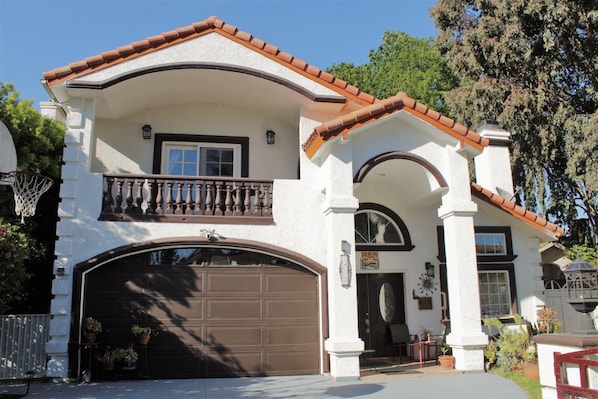 Stunning two-story residence with a central entrance, balcony, and well-manicured front yard.