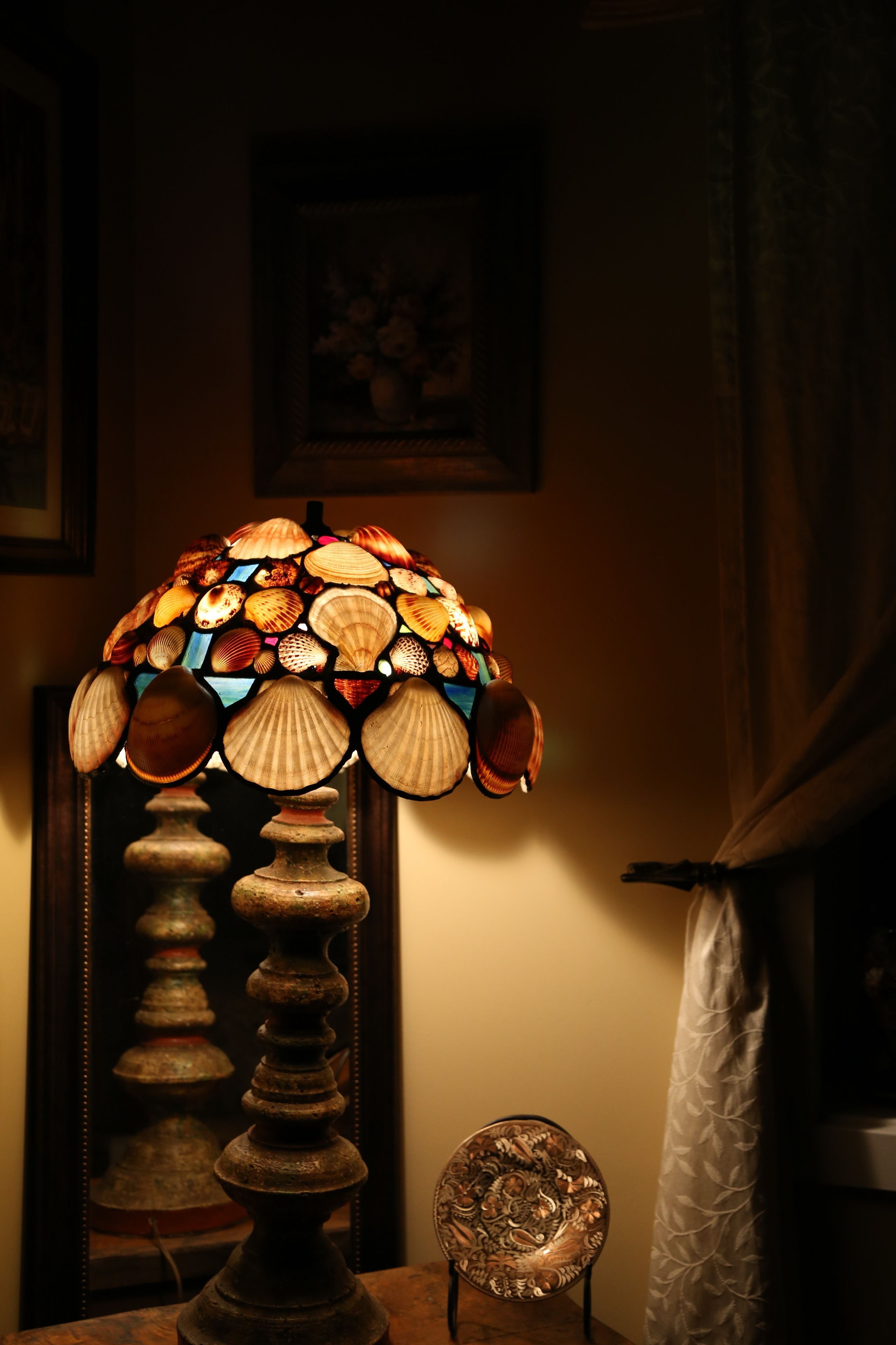 Una lámpara de vitral con diseño floral, un atril de madera y un plato decorativo.