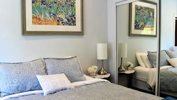 A bedroom with a bed, a nightstand, a lamp, and two framed paintings on the wall.
