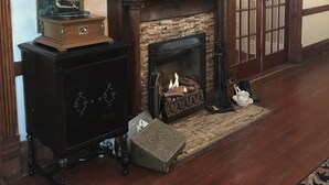 A room with a fireplace, a gramophone, and a wooden cabinet.
